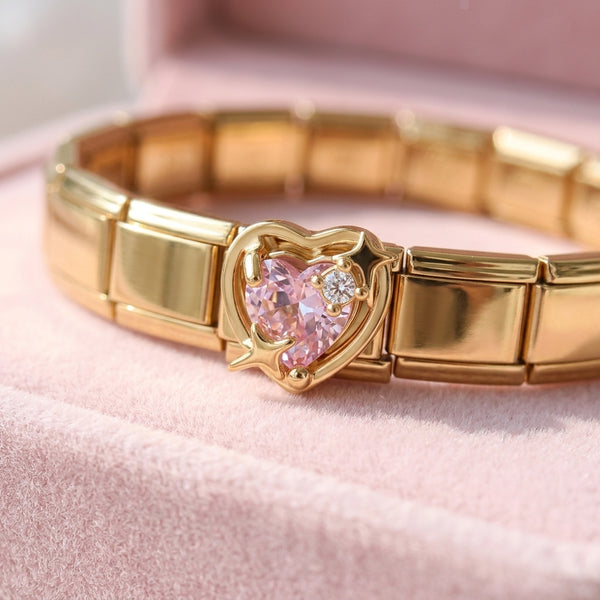 Gold 9mm Italian charm bracelet with a heart-shaped pink gemstone on a pink background