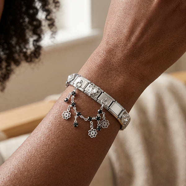 Silver 9mm Italian charm bracelet with floral drops and black beads on a wrist against a neutral background