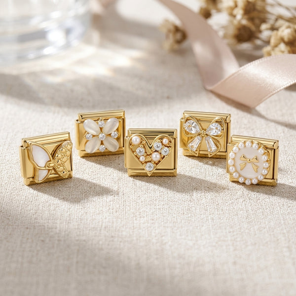 Set of gold 9mm Italian charms with pearl and crystal floral and heart designs on a soft fabric background