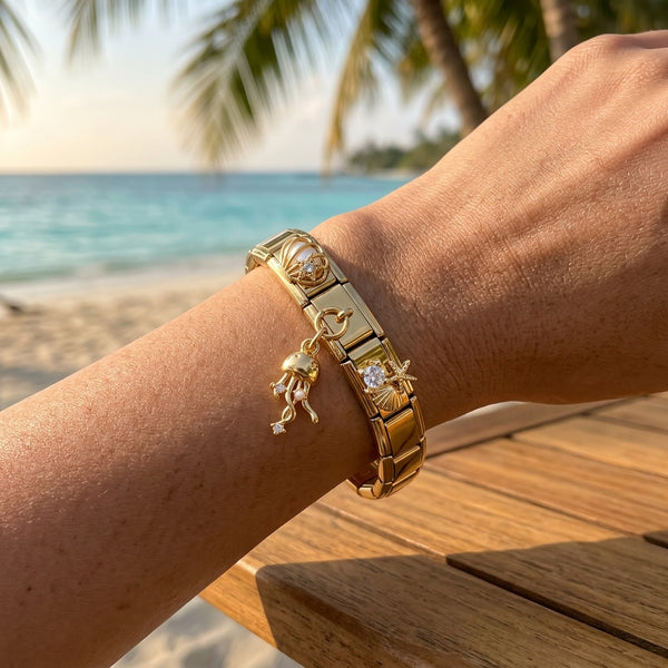 Gold 9mm Italian charm bracelet with ocean theme charms on a wrist by the beach