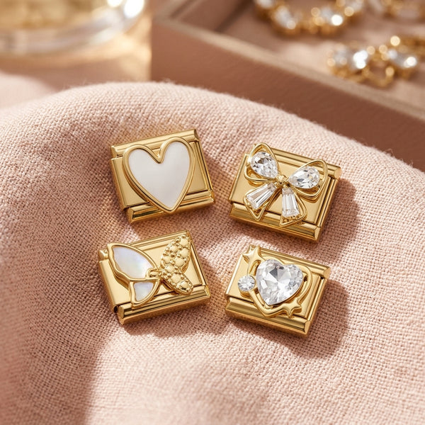 Assorted gold 9mm Italian charms in white heart, butterfly, baguette crystal bow and heart on pink fabric