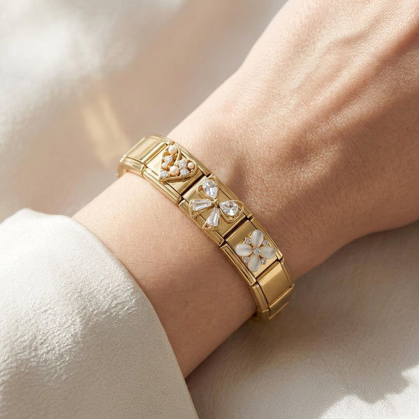 Gold 9mm Italian charm bracelet with pearl heart, floral and butterfly designs on a wrist against a neutral background